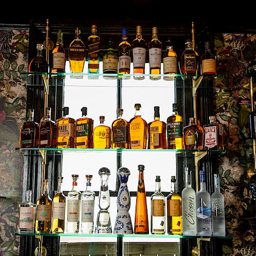 The image shows shelves filled with various bottles of liquor displayed against a decorative background.