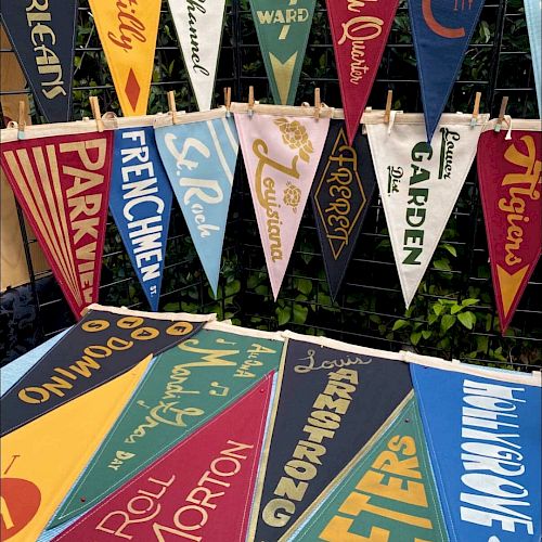 A colorful display of pennant banners from various famous universities and colleges, arranged in rows and bright hues.