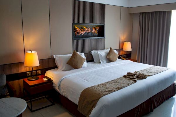 A neatly made bed with pillows, lamps on side tables, and a decorative wall piece in a cozy, softly lit room with curtains.