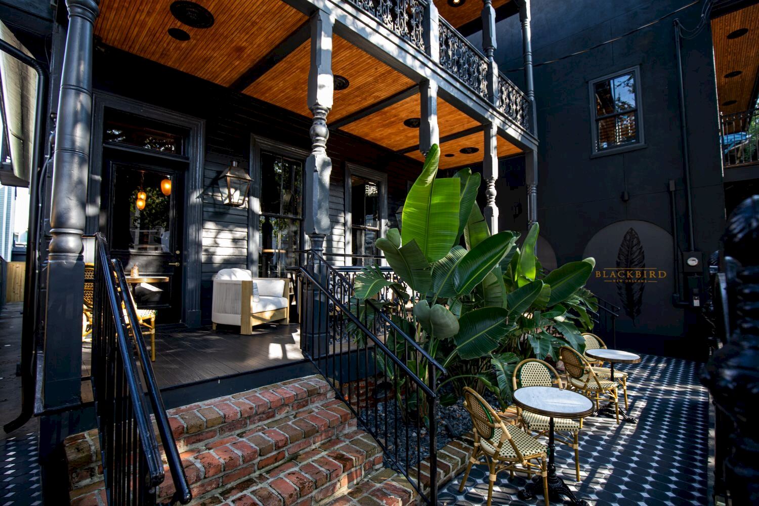 A black building with a balcony and stairs leading to a seating area.