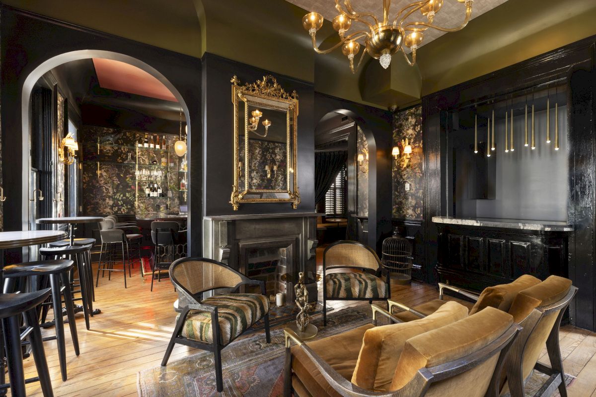 A luxurious hotel lobby bar with a fireplace, chandelier, and comfortable seating area.