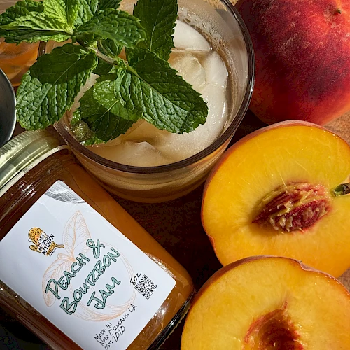 A jar of peach mango jam, fresh mint garnish, creamy yogurt, and sliced peaches on a wooden surface. Delicious and refreshing.