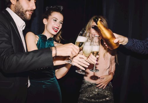A group of friends toasting with champagne flutes at a party, dressed stylishly and smiling as drinks are poured.
