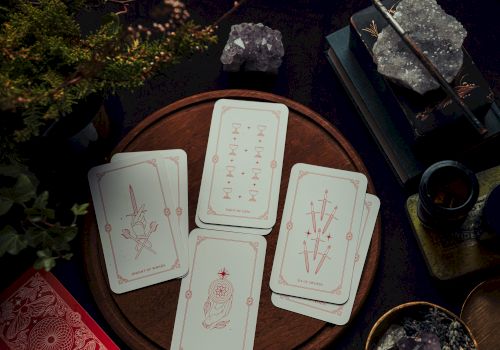 A tarot card spread on a wooden board with crystals, a wand, and candles&mdash;fortunes and mystic symbols in candlelit shadow.