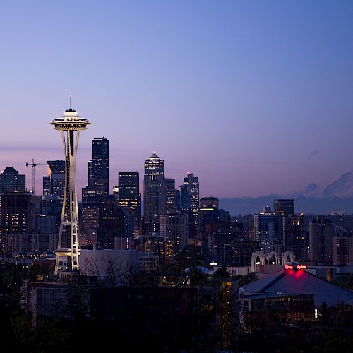 The image shows the Seattle skyline at dusk with the Space Needle and Mount Rainier in the background.