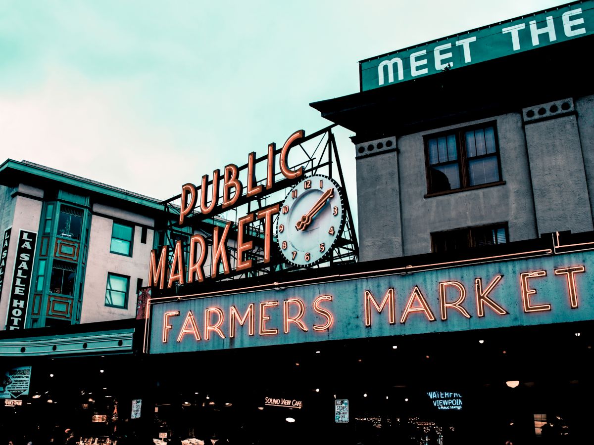 The image shows the signage of a well-known public market, featuring "Public Market" and "Farmers Market" with a clock in between.