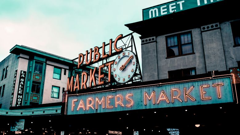 The image shows the signage of a well-known public market, featuring "Public Market" and "Farmers Market" with a clock in between.